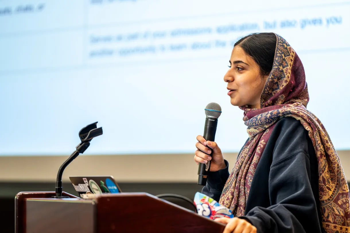 Facilitator in headscarf speaking into microphone