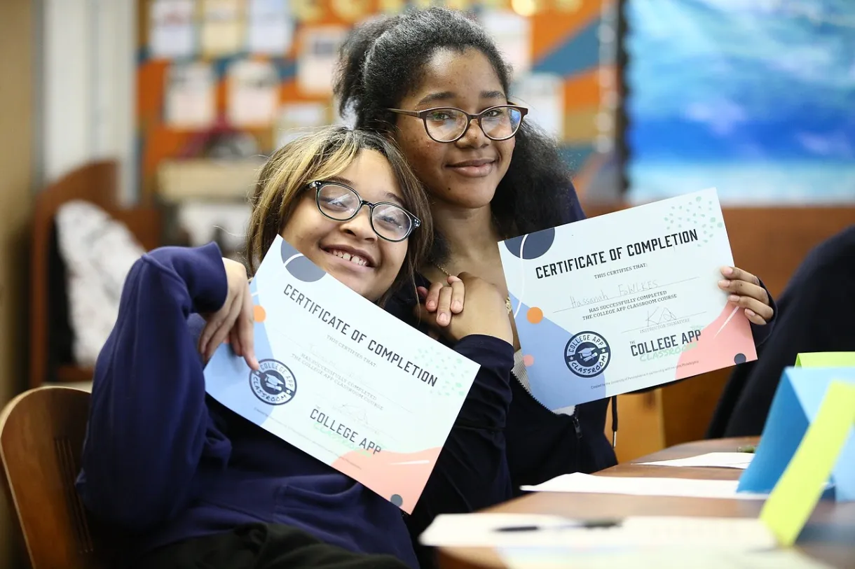 Two students holding up their College App Classroom certificates